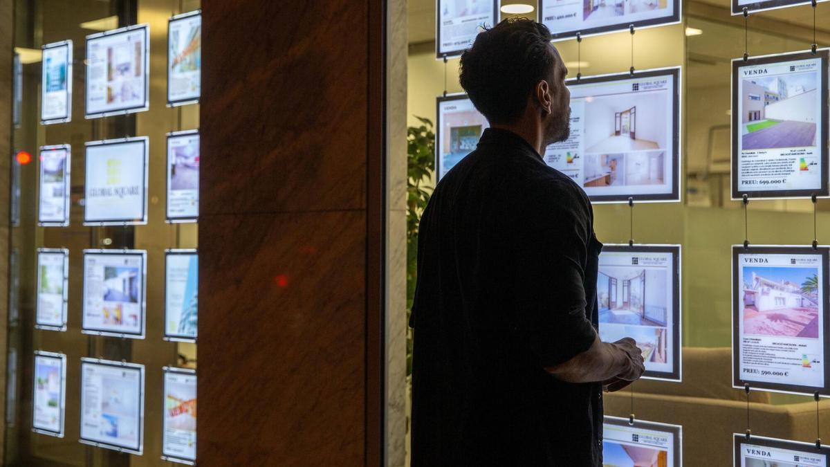 Un joven mira la oferta inmobiliaria de una agencia en el Eixample.