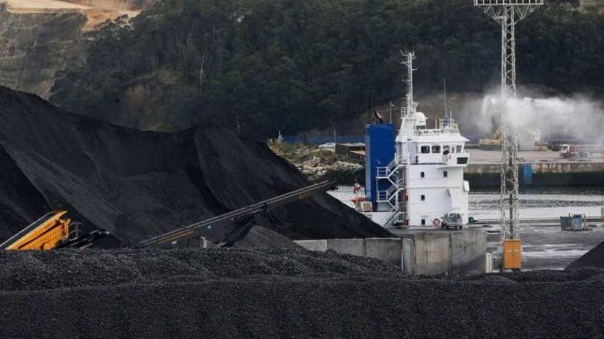 Aspersores de agua actuando sobre montañas de carbón en el puerto de Avilés.