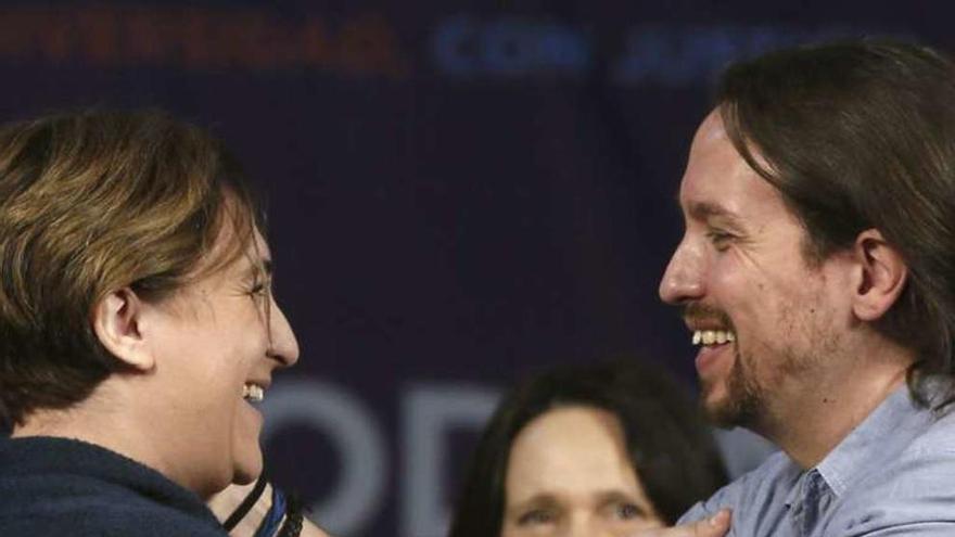 Ada Colau y Pablo Iglesias se abrazan ante Carolina Bescansa. // Efe