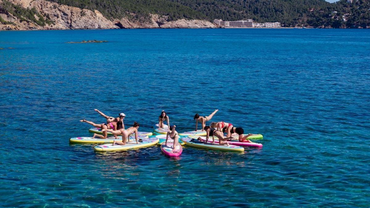 Mujeres haciendo actividad física en sus paddles surf en medio del mar
