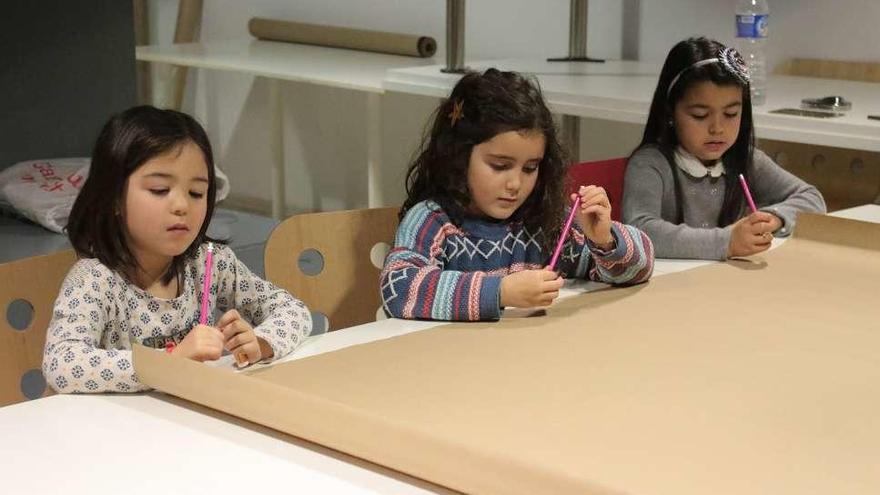 Tres niñas meditan ante el mural en blanco antes de comenzar a dibujar.