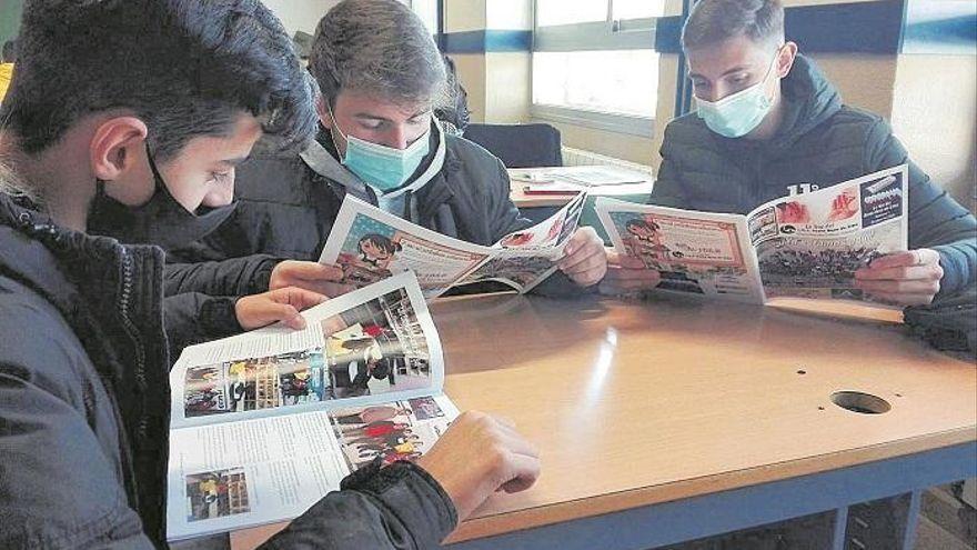 Unos alumnos leen un periódico escolar.