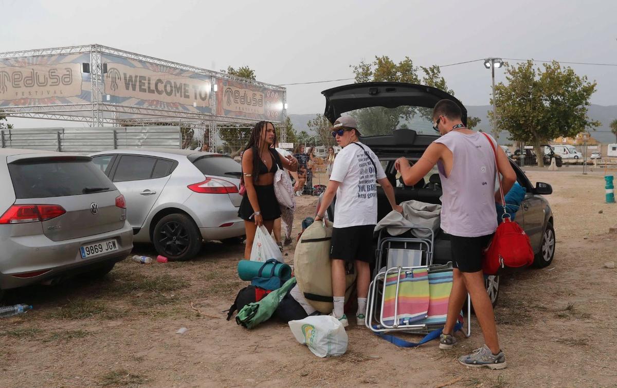 Tres jóvenes descargan un vehículo con los enseres para alojarse en el camping.