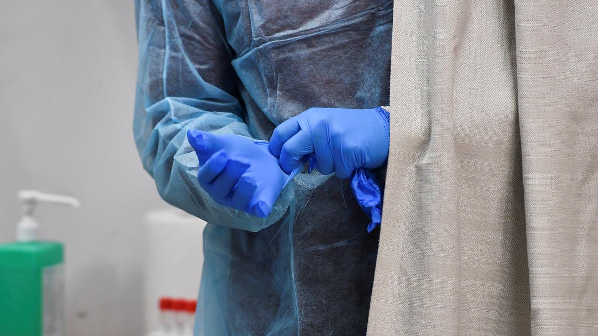 Un trabajador sanitario se coloca los guantes para realizar test de covid a pasajeros procedentes de China, en el aeropuerto de Malpensa, en Milan, este jueves.