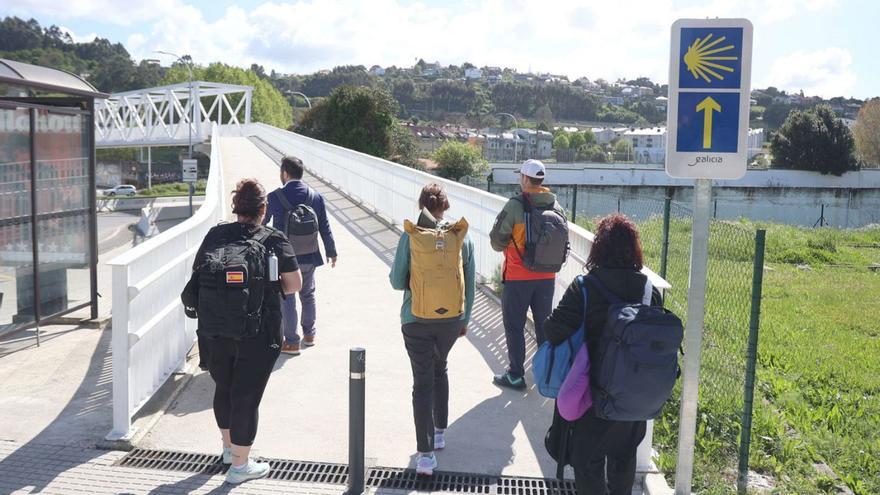 Caminantes cruzan la pasarela de Pedralonga, parte del Camino Inglés. | Iago López
