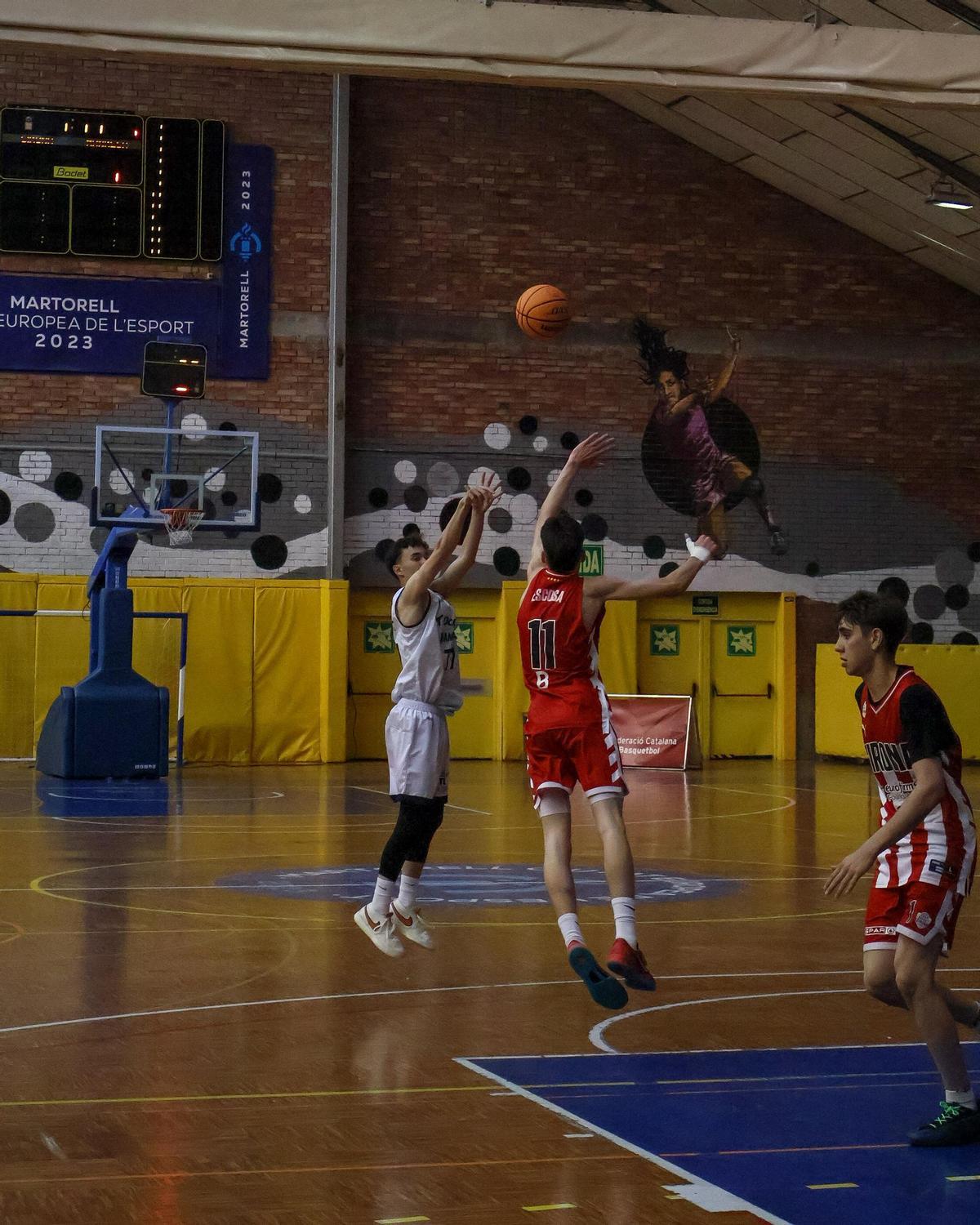 Carles Méndez llançant un triple davant Arnau Escosa