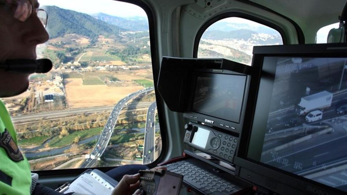 Un agente de Tránsit de los Mossos controla la cámara del helicóptero mientras sobrevuela el Baix Llobregat.