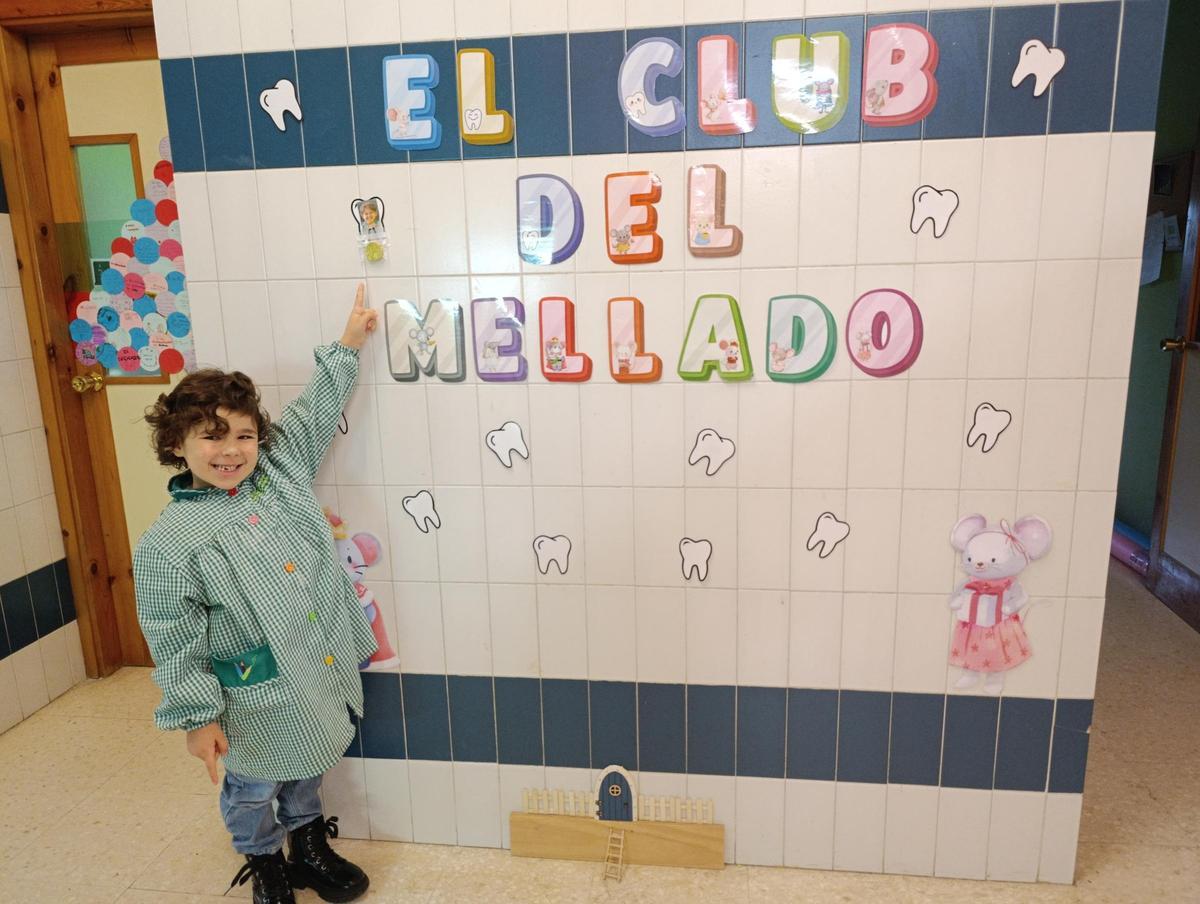 Sofía López, orgullosa, muestra su moneda de chocolate y su foto expuesta en el mural.