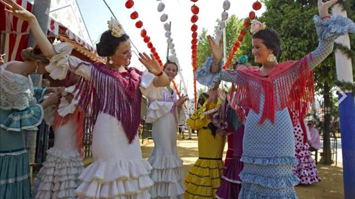 Jóvenes vestidas de flamenca bailan sevillanas en el Real de la Feria de Abril