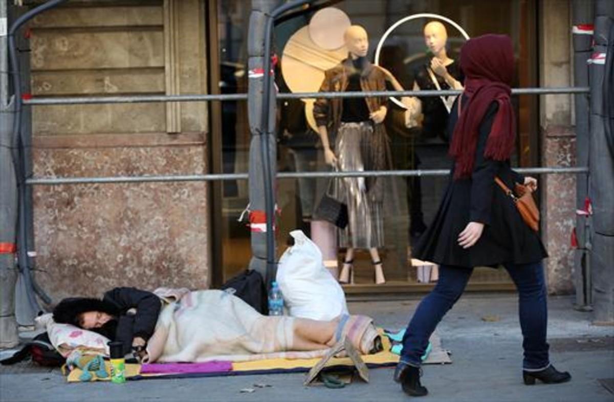 Un hombre duerme en la calle, en el paseo de Gràcia de Barcelona Un hombre duerme en la calle, en el paseo de Gràcia de Barcelona