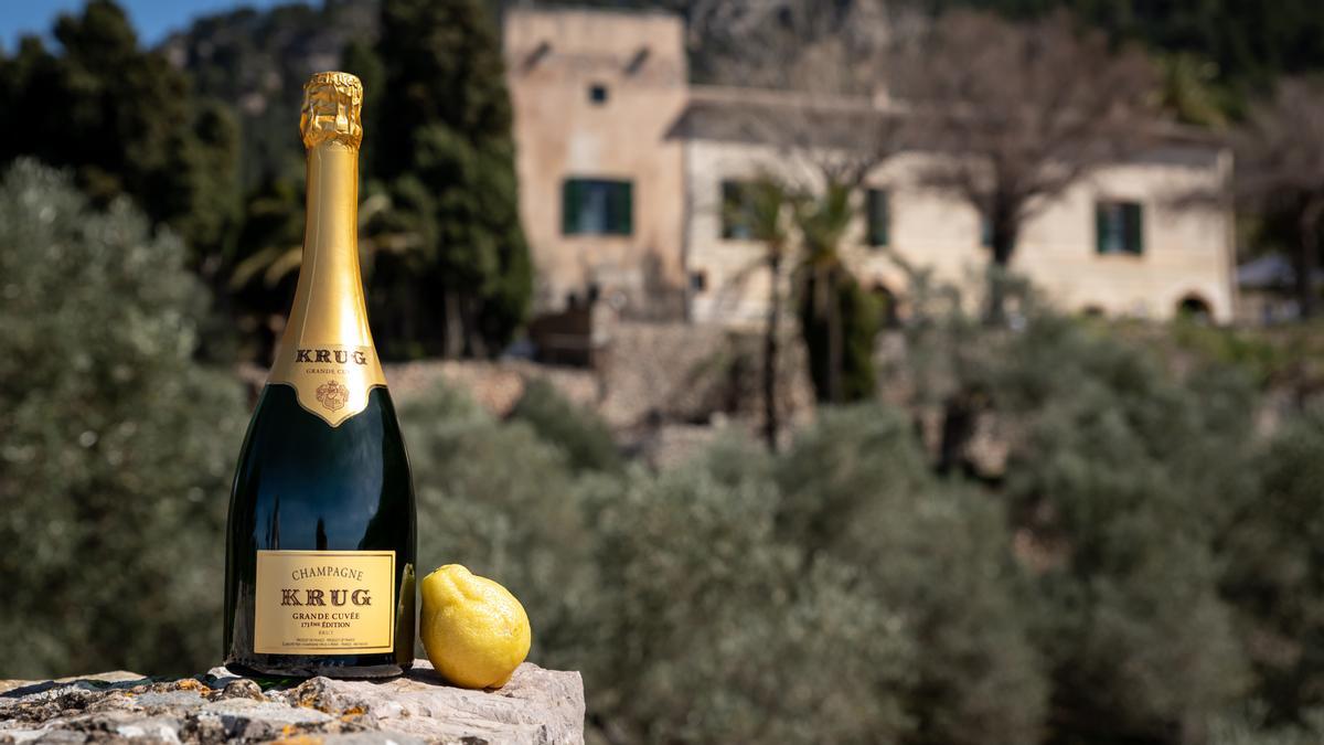Una botella de champán Krug, con el edificio de Miramar (Mallorca), al fondo.