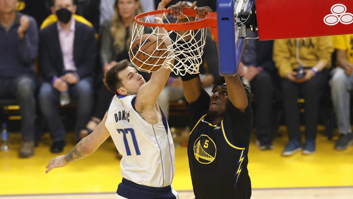 Kevon Looney, de los Warriors, machaca el aro de los Dallas Mavericks pese a la oposición de Luka Doncic.