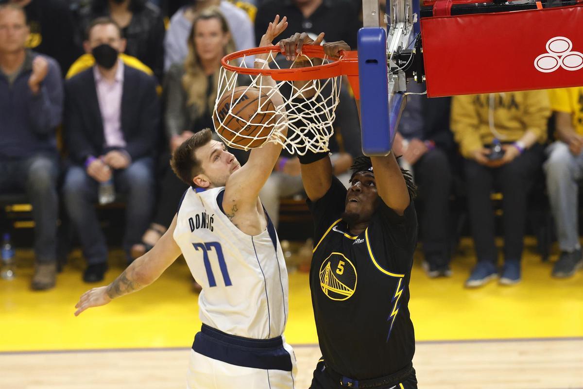 Kevon Looney, de los Warriors, machaca el aro de los Dallas Mavericks pese a la oposición de Luka Doncic.