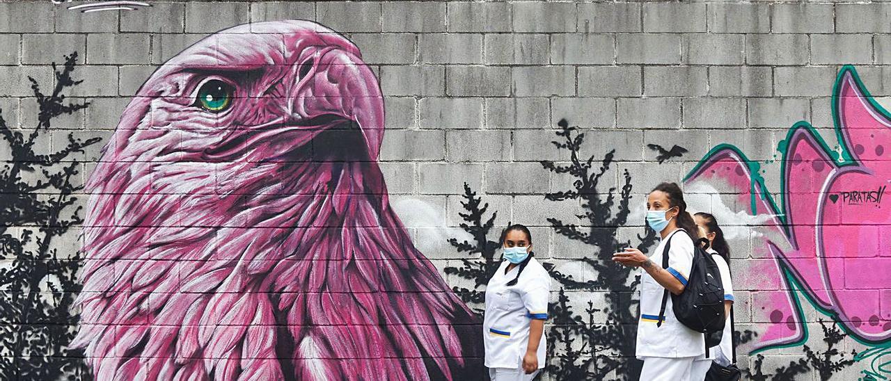 Tres mujeres pasan por delante de uno de los grafitis pintados en el estadio Suárez Puerta en el transcurso del Festival de la cultura urbana (Focart), celebrado en Avilés del 11 al 20 de junio.