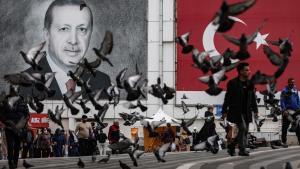 Una bandada de palomas alza el vuelo en una plaza decorada con un retrato del presidente turco, Recep Tayyip Erdogan.