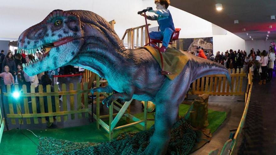 Un niño a lomos de un dinosaurino en la muestra en otra población. | Cedida