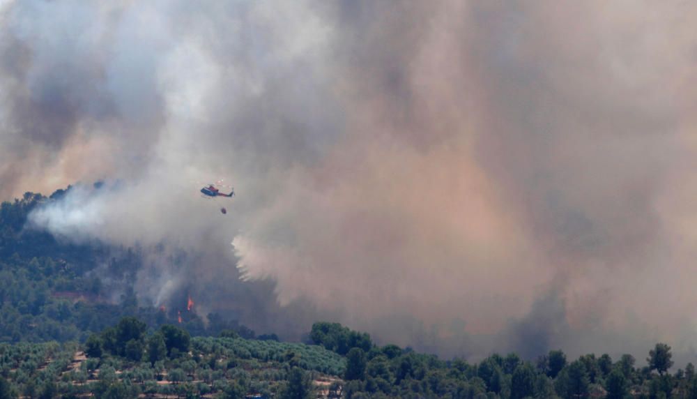 A helicopter drops water over a fire during a ...