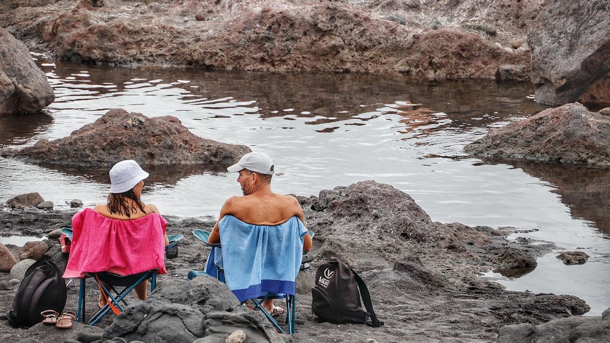 Dos bañistas se refrescan en los charcos de la costa lagunera.