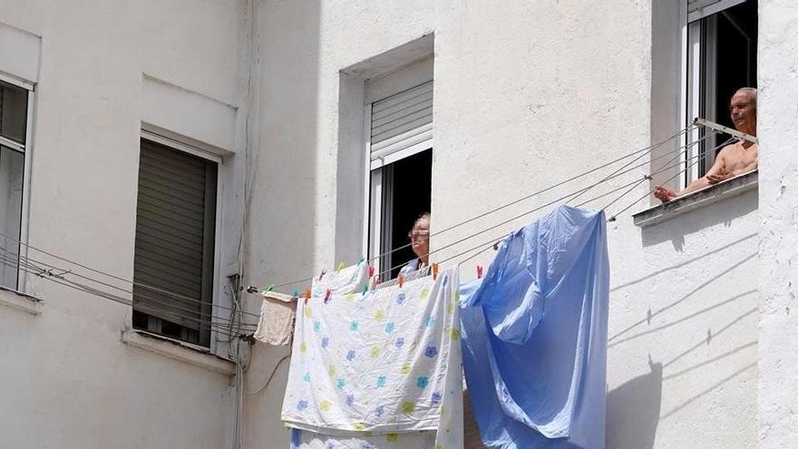 Dos personas mayores toman el sol en la ventana vivienda en Madrid.