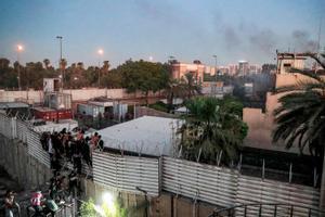 Los partidarios del clérigo chiíta iraquí Moqtada al-Sadr escalan la valla frente a la embajada sueca en Bagdad.