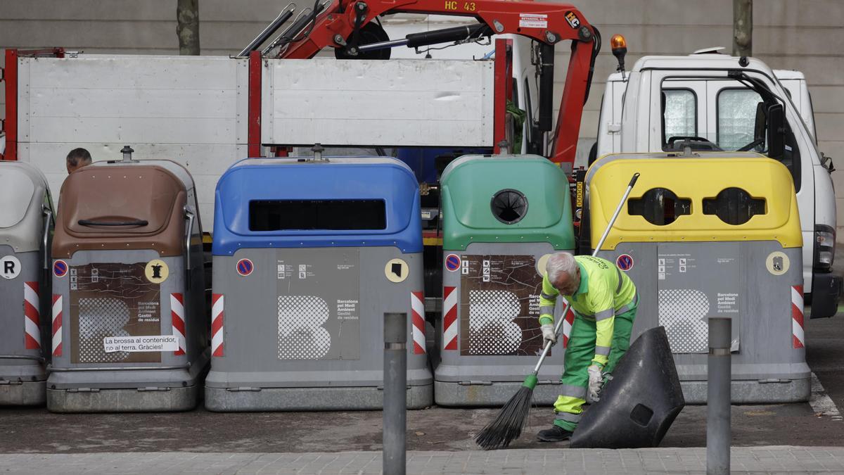 Un operario de la limpieza de Barcelona delante de unos contenedores y un camión de la basura, en el distrito de Nou Barris.