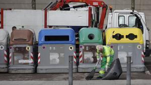 Un operario de la limpieza de Barcelona delante de unos contenedores y un camión de la basura, en Nou Barris.