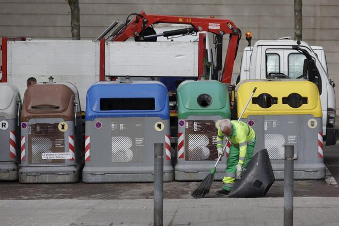 Un operario de la limpieza de Barcelona delante de unos contenedores y un camión de la basura, en Nou Barris.