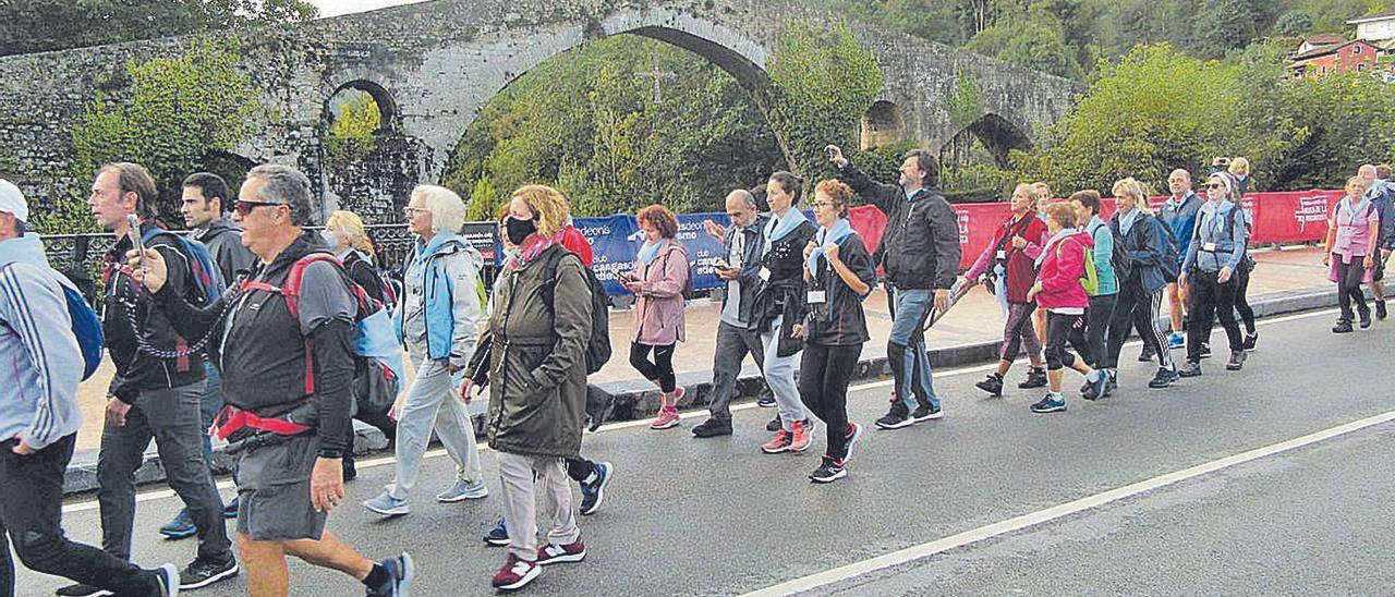 Algunos de los participantes en la marcha del Centro Asturiano de Oviedo a Covadonga, ayer, a su paso por las inmediaciones del puente “romano” de Cangas de Onís. | J. M. C.