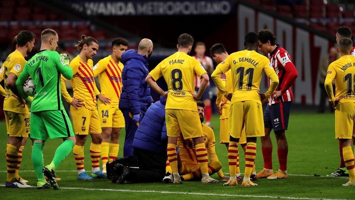 Piqué se lamenta de su grave lesión en la rodilla derecha rodeado de jugadores del Barça y del Atlético.