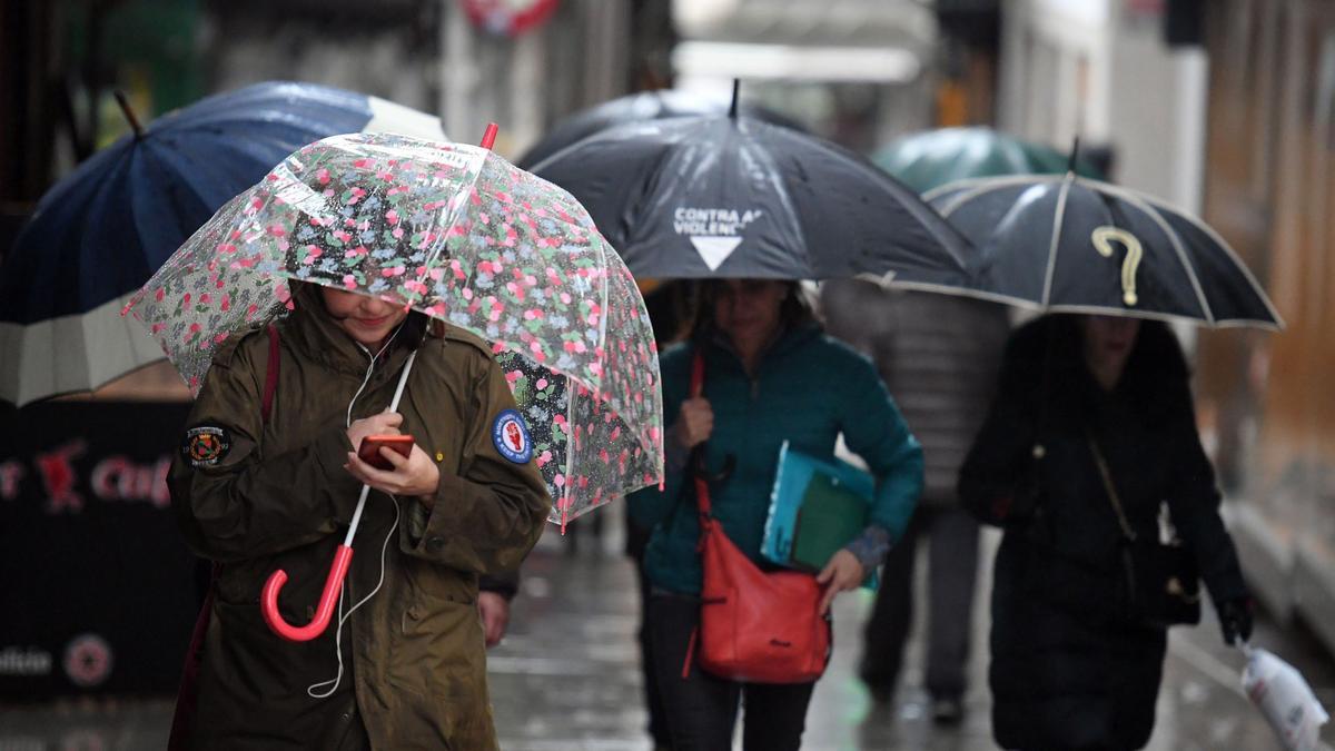 Gente protegiéndose de la lluvia en A Coruña.