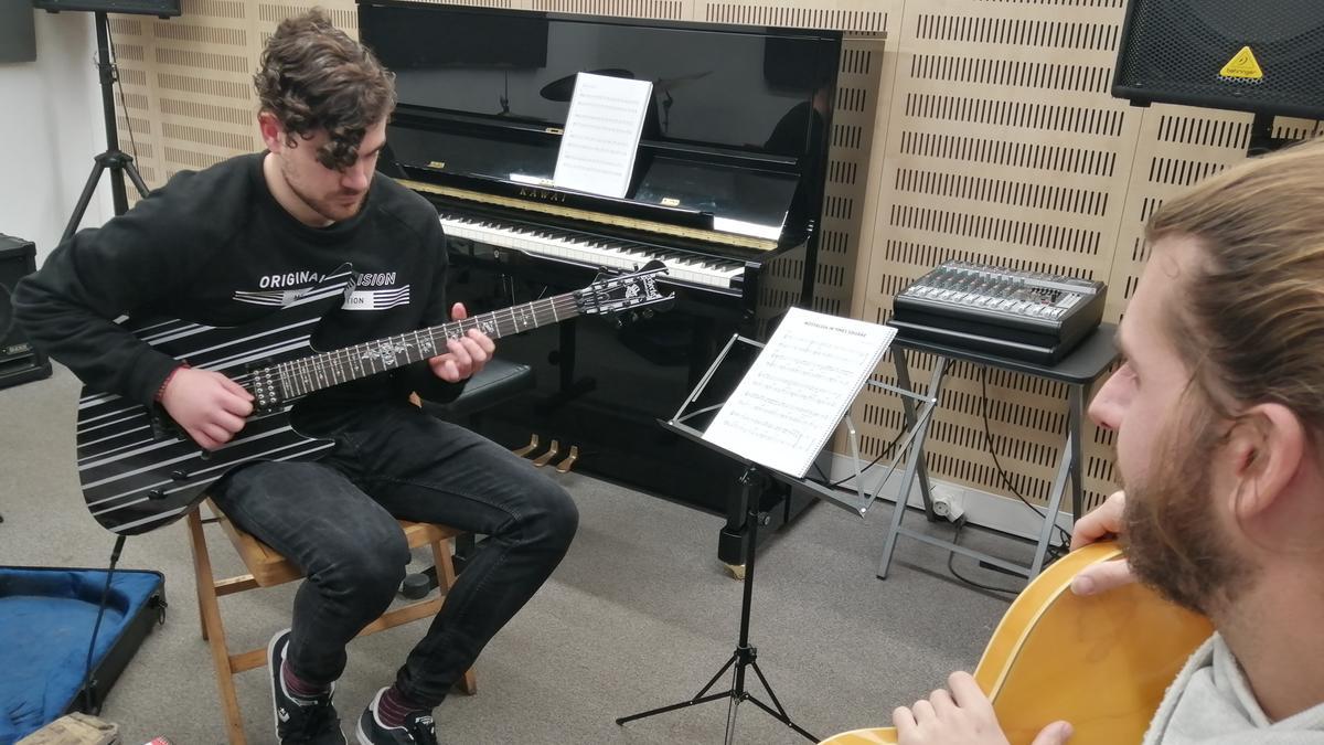 Un alumne de guitarra tocant davant del seu professor.