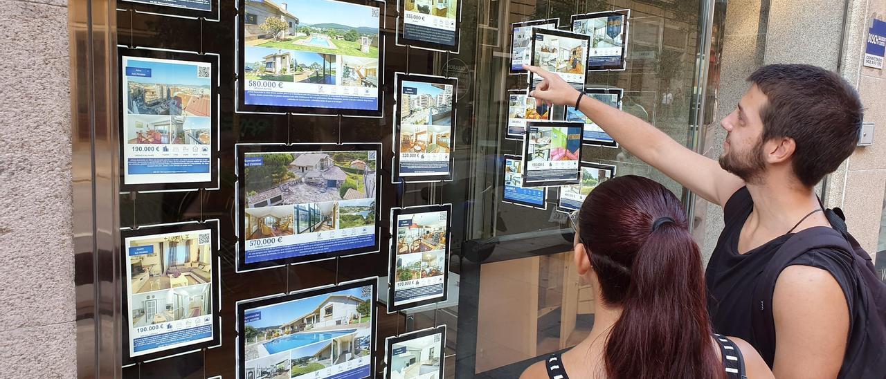 Gente viendo el escaparate de una inmobiliaria en Vigo.