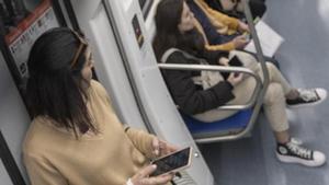 Una mujer con un móvil en el metro de Barcelona.