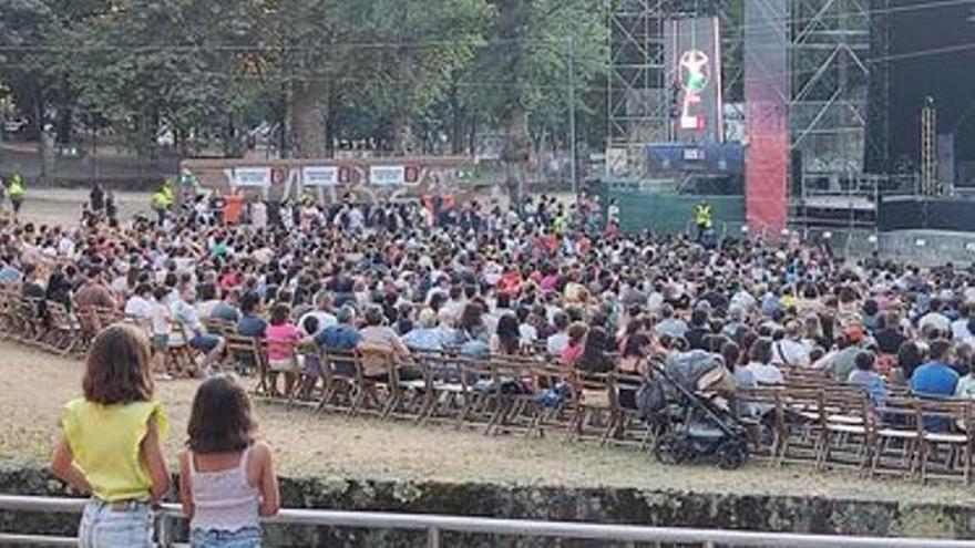 Dos niñas observan varias sillas vacías desde las gradas exteriores del auditorio de Castrelos