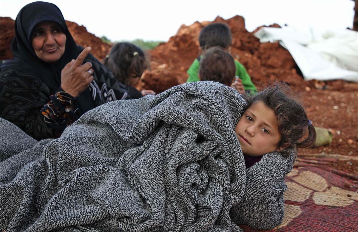 Los sirios desplazados se reúnen en un campo cerca de un campamento para personas desplazadas en la aldea de Atme, en la provincia de Idlib. En el olivar de Atme, docenas de familias pasaron la noche en colchones delgados o mantas sobre las alfombras en la tierra. En la base de los árboles que han elegido como refugio, han almacenado el mínimo indispensable para una vida al aire libre.