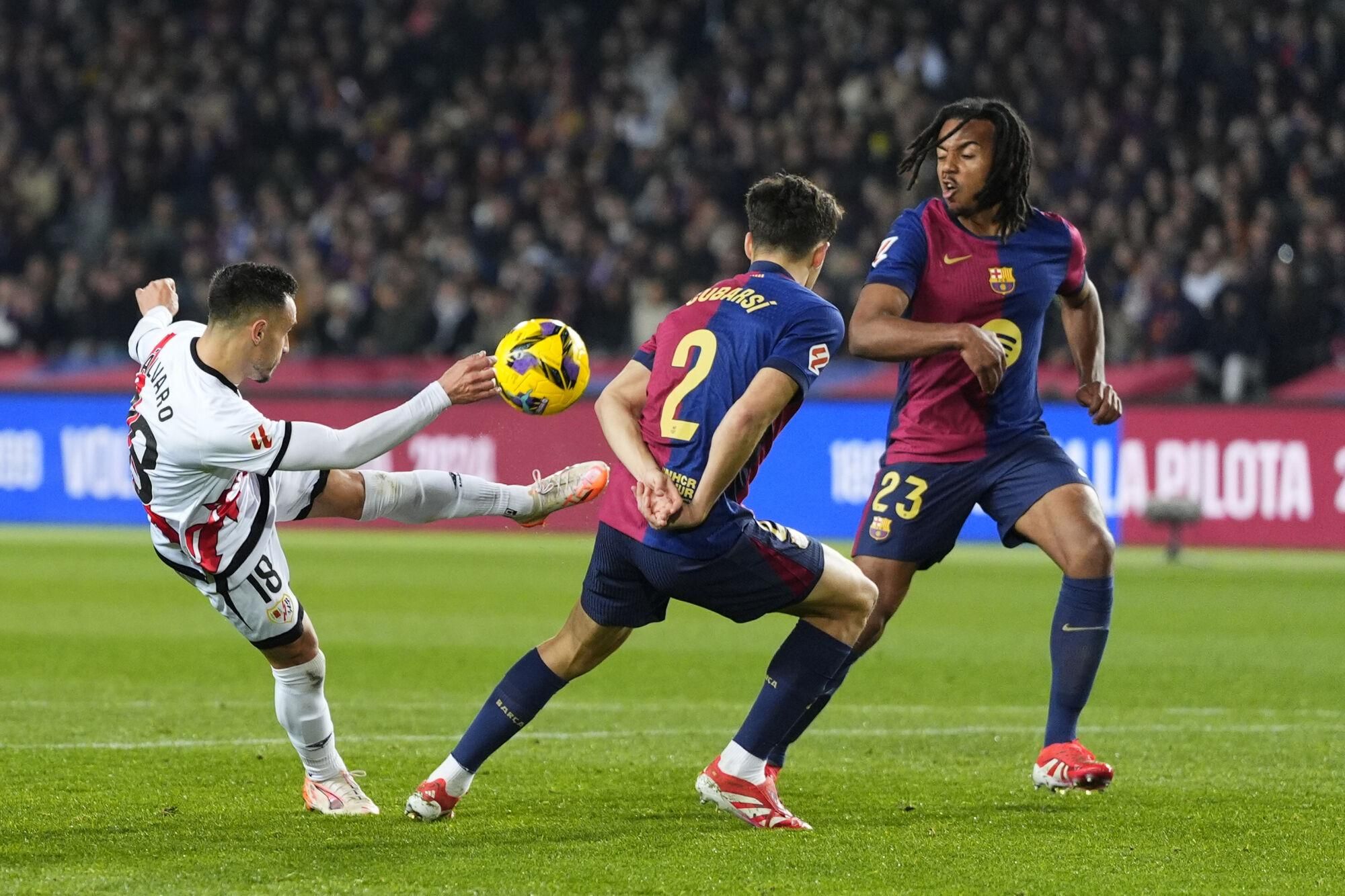 BARCELONA, 17/02/2025.- El centrocampista del Rayo Álvaro García (i) remata ante Pau Cubarsí (c) y Jules Koundé, ambos del Barcelona, durante el partido de LaLiga de fútbol que FC Barcelona y Rayo Vallecano disputan este lunes en el estadio Lluis Companys. EFE/Siu Wu