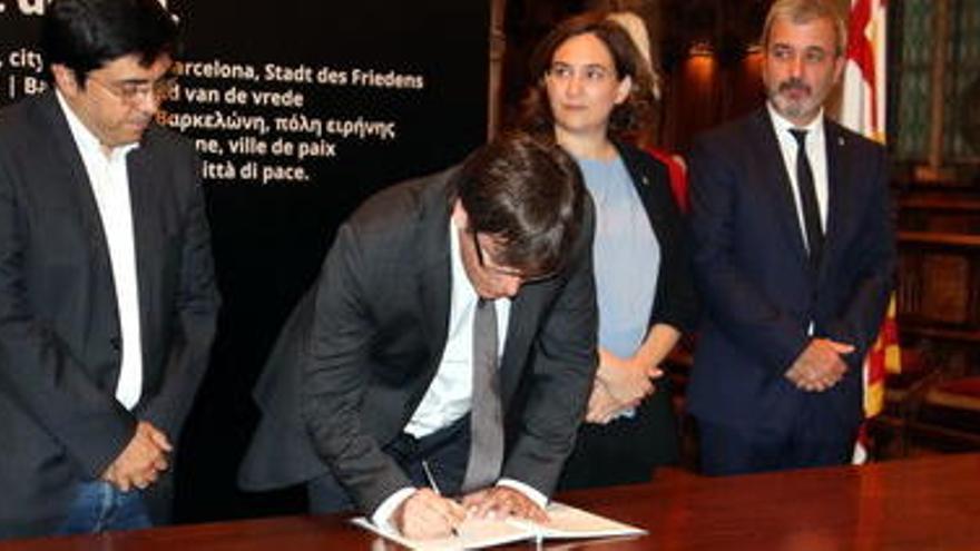 El president Puigdemont signant el llibre de condol al Saló de Cent acompanyat per l&#039;alcaldessa Colau