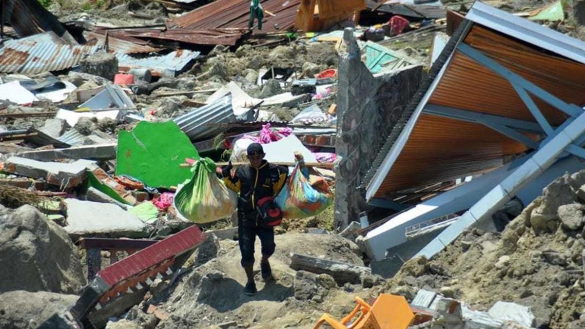 Un hombre carga objetos personales entre los escombros de un edificio derrumbado por el terremoto, en la ciudad indonesia de Palu.