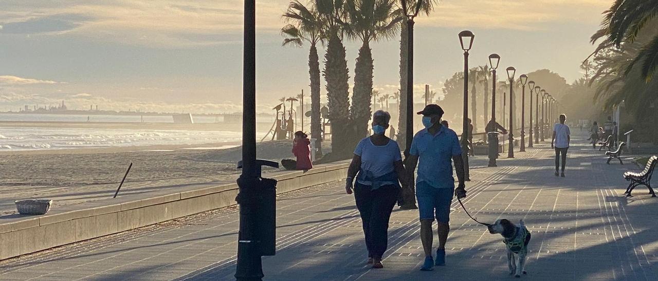 Dos personas caminan con su perro por el paseo marítimo de Benicàssim.