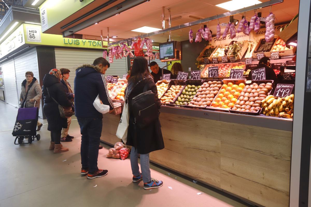 Varias personas hacen fila en un puesto del mercado, en Zaragoza.