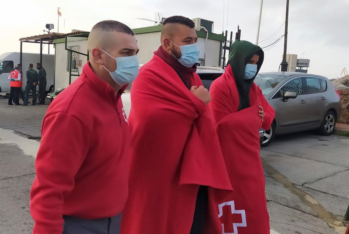 Dos inmigrantes marroquís son atendidos por un miembro de la Cruz Roja tras llegar a nado a Ceuta el pasado finde semana.