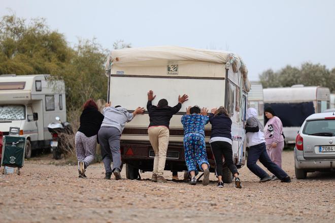 Varios residentes en el asentamiento ayudan a mover una de las caravanas.