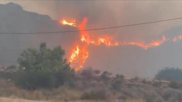 Un avió llança aigua sobre un dels focus de l’incendi.