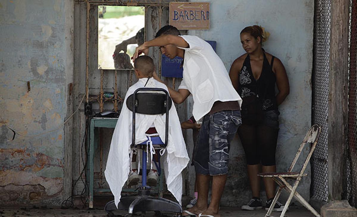Una perruquer cubà amb llicència privada talla els cabells d’un noi aquest dijous a l’Havana