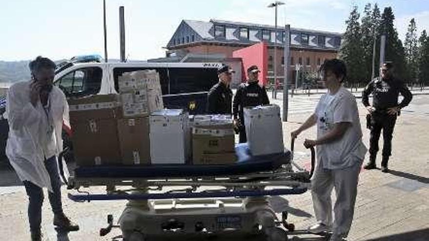Dos sanitarios trasladan en una camilla el material cedido por el Cuerpo Nacional de Policía al HUCA.