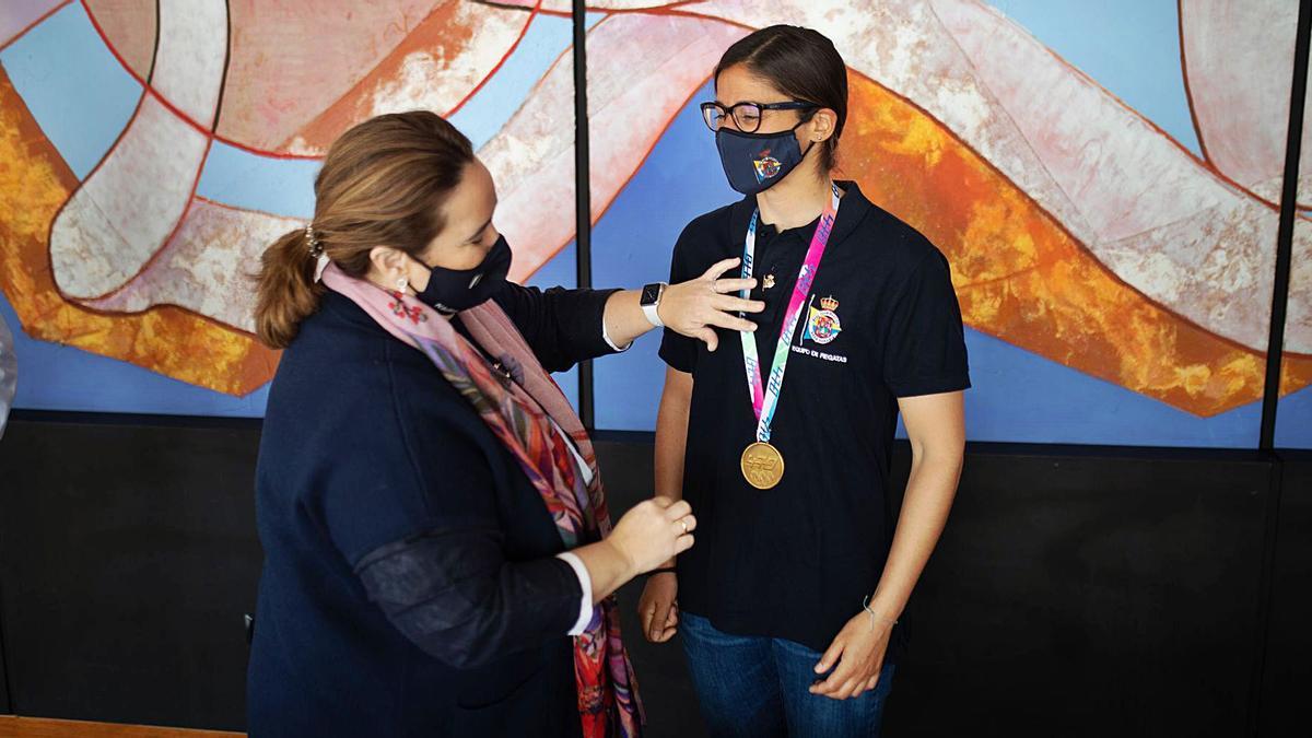 Maica López Galán, president of the Real Club Náutico de Gran Canaria, places the club's gold badge on world champion Patricia Cantero yesterday at the club's headquarters.  |  |  LP / DLP