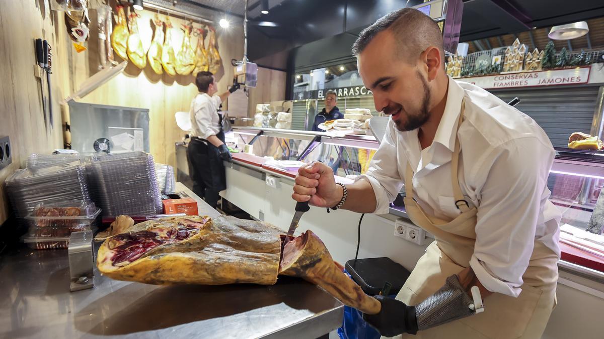 Un hombre corta jamón en un puesto del Mercado Central.