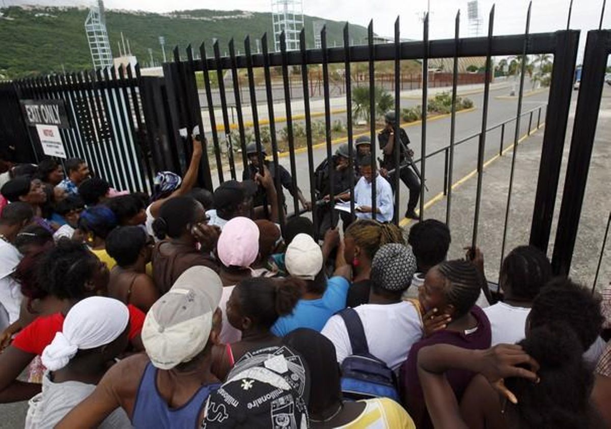 Diverses famílies esperen notícies dels seus membres i amics davant de les portes de l’Estadi Nacional de Jamaica, on hi ha més de 600 persones detingudes en l’operació al barri de Tivoli Gardens.