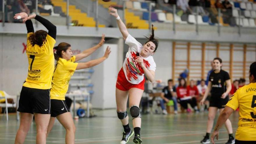 Una jugadora del Balonmano Gijón se dispone a lanzar a portería ante el intento de bloqueo de dos jugadoras rivales.