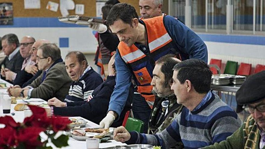 Un voluntario sirve la cena a los asistentes.